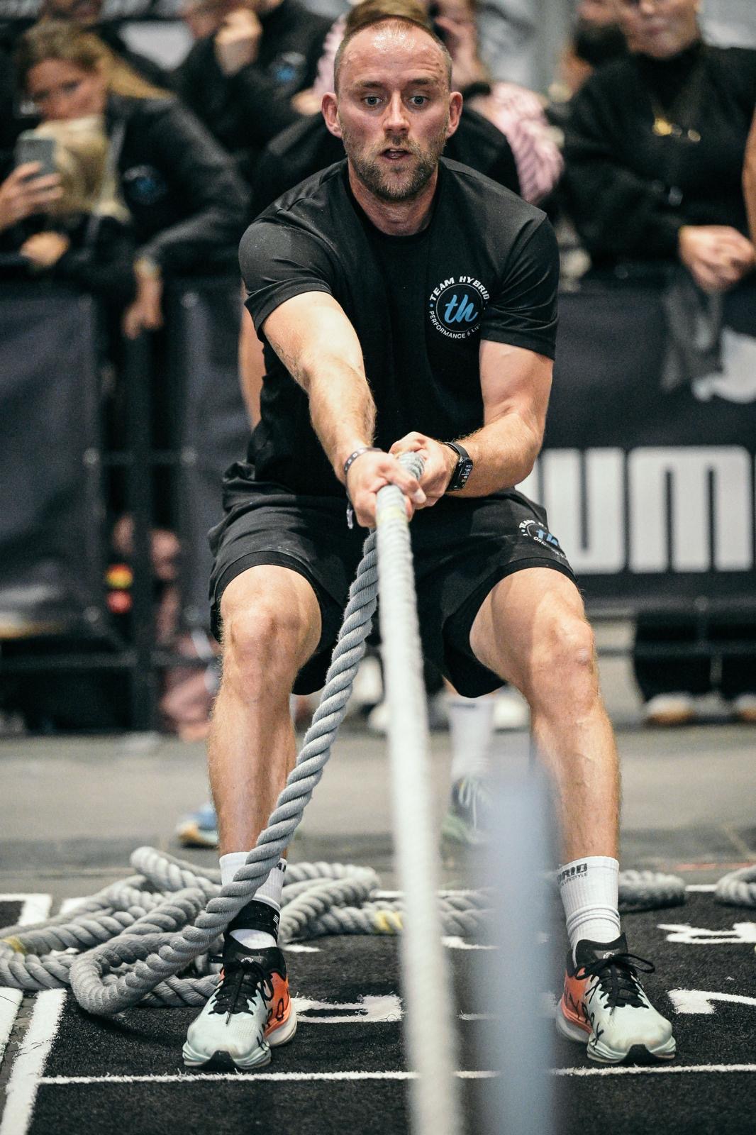 TEAM-HYBRID-Athlet zieht beim Sled Pull das Tau in der Hamburg Messe beim HYROX Hamburg 2025