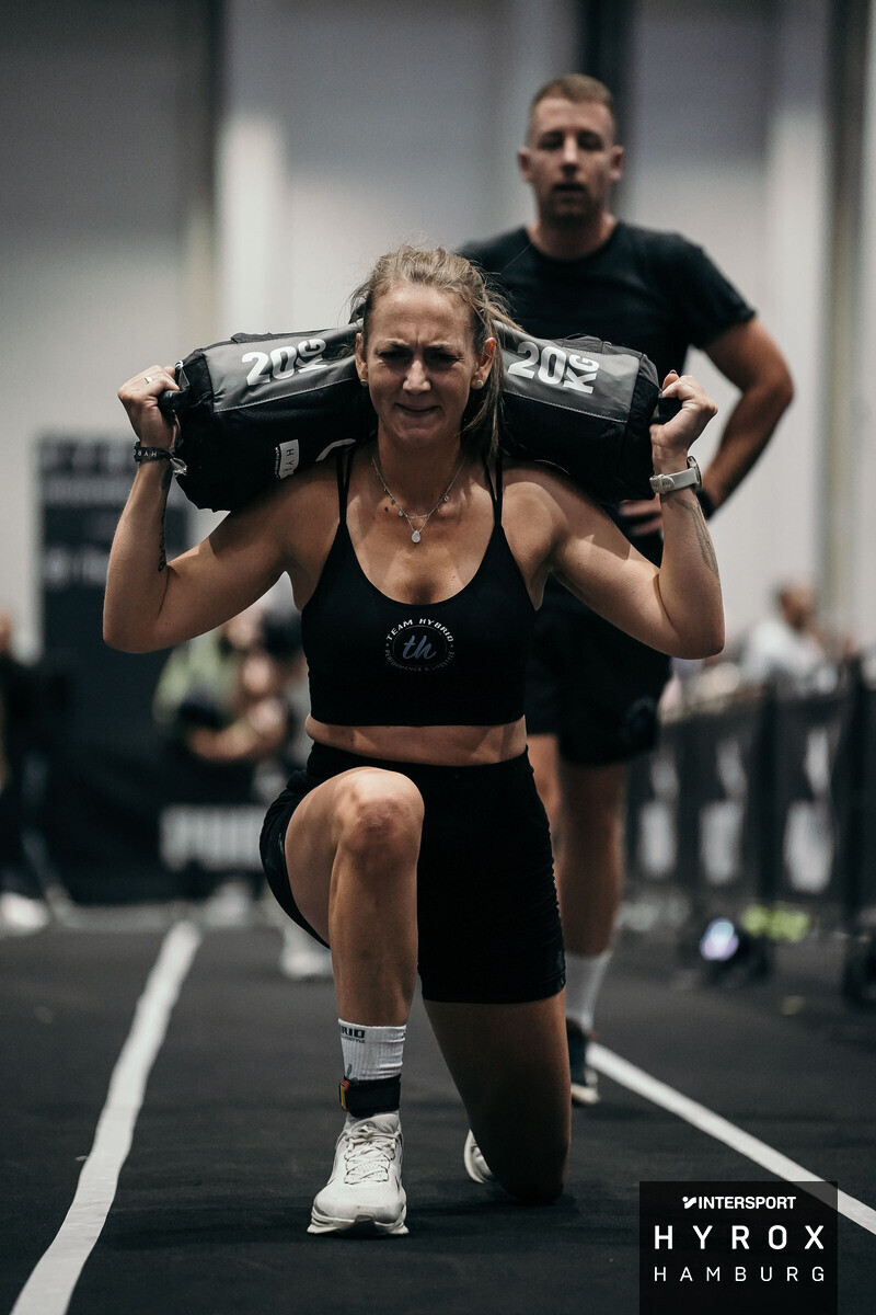 TEAM-HYBRID-Athletin bei den Sandbag Lunges mit 20-kg-Sandbag in der Hamburg Messe beim HYROX Hamburg 2025