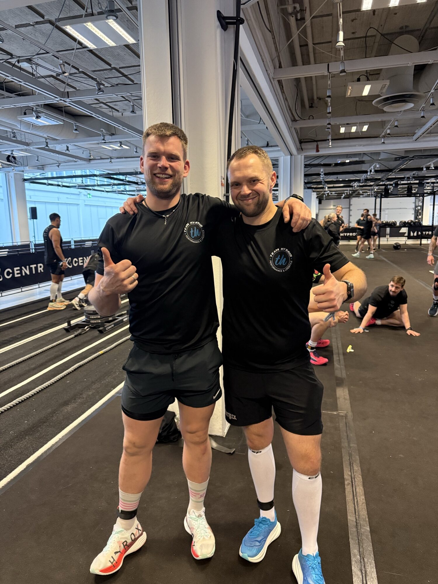 Zwei TEAM-HYBRID-Athleten mit Daumen hoch beim HYROX Kopenhagen 2026 im Bella Center