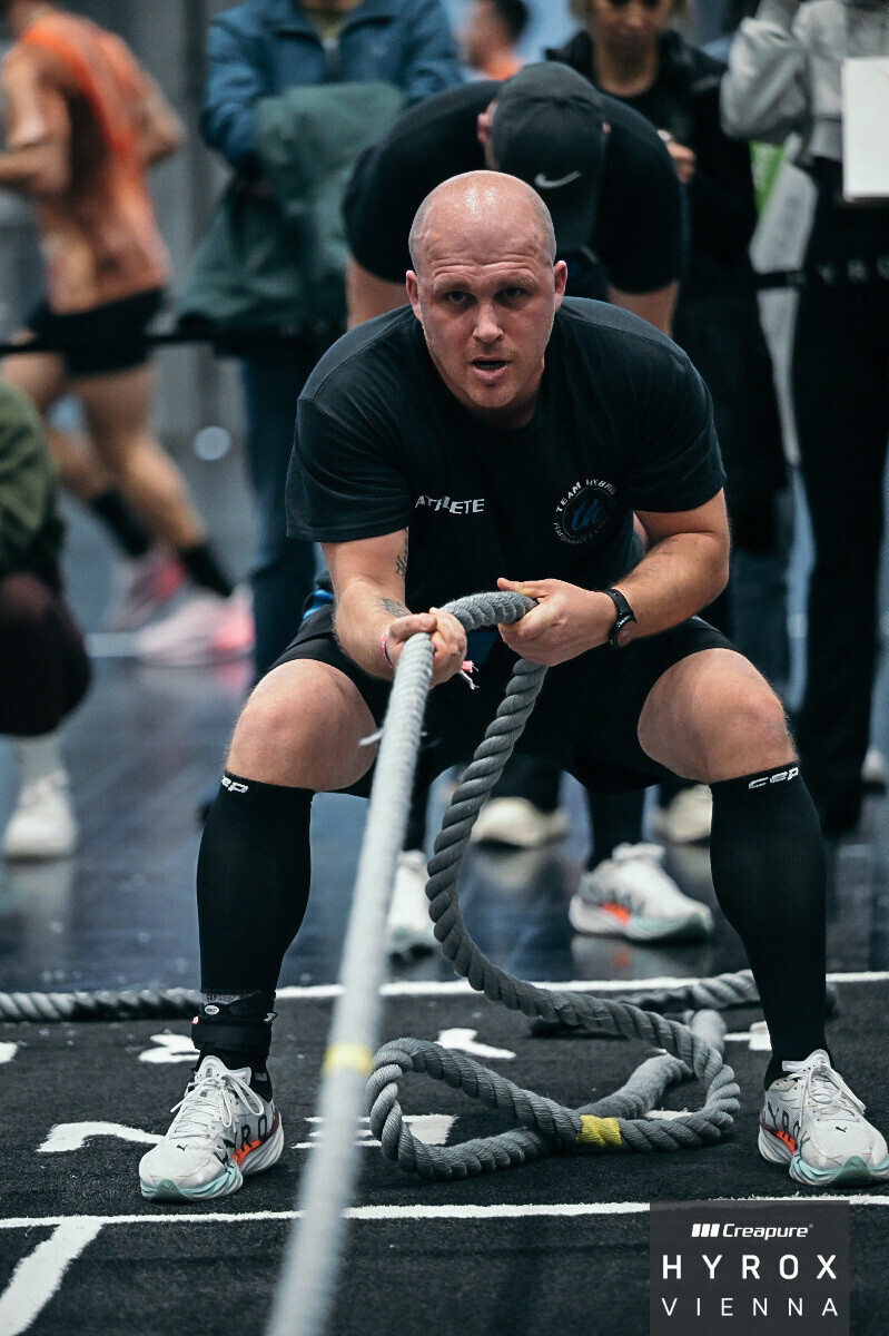 TEAM-HYBRID-Athlet beim Sled Pull auf der Wettkampffläche des HYROX Wien 2026